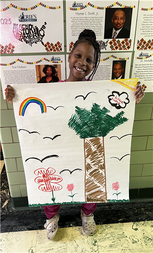 London, an Edison student, shows off a picture of her vision of a wonderful world. Features a rainbow, tree, flowers and bird